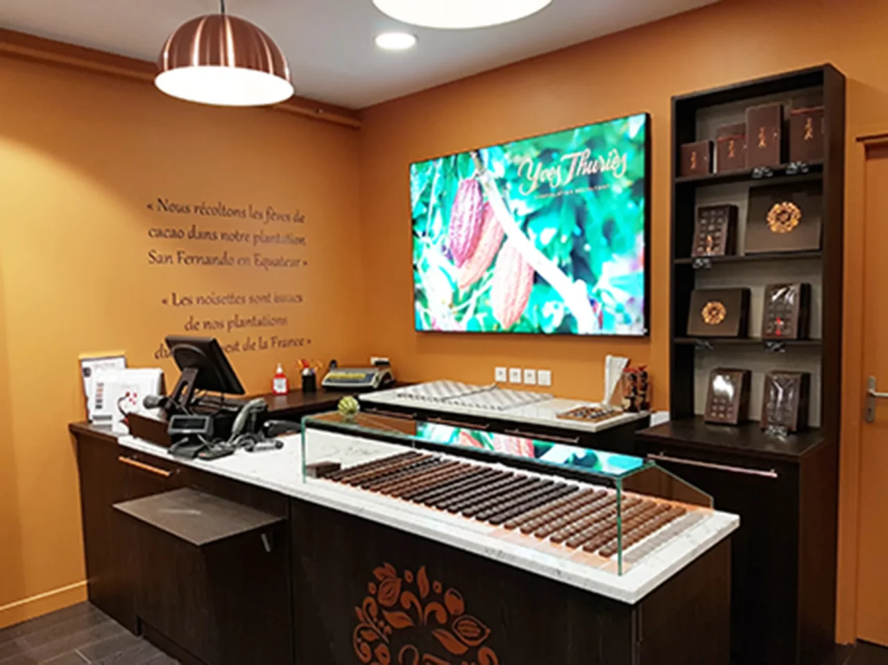 Zone de caisse fonctionnelle et chaleureuse dans une chocolaterie, conçue par ECRT pour faciliter le service client tout en valorisant les produits.